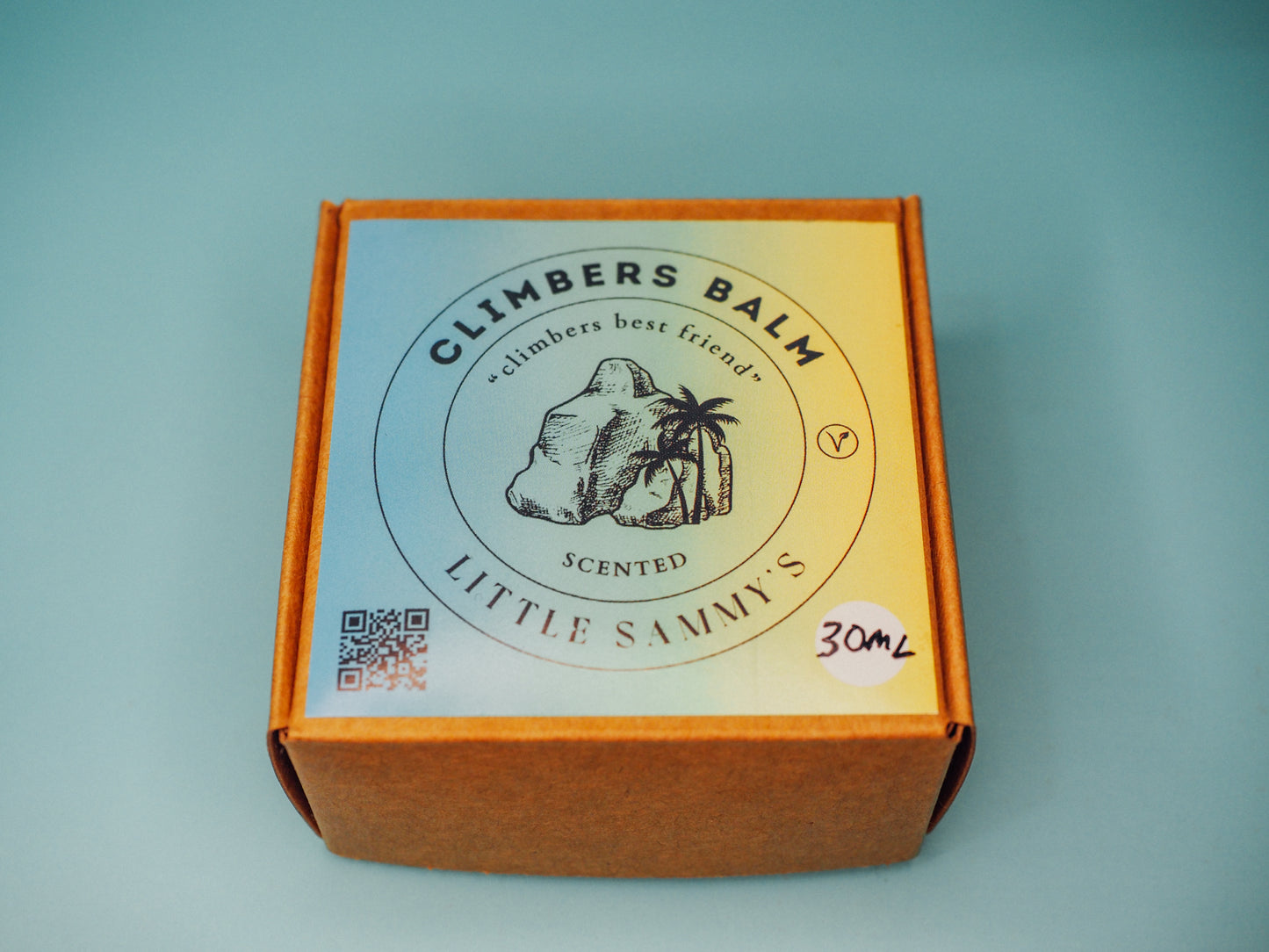 A closed premium kraft box for Little Sammy's Scented Climbers Balm Travel Bundle, featuring a crisp label with a QR code, sits against a light blue backdrop, hinting at the quality skincare journey within for climbers.