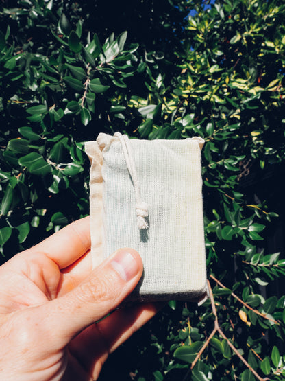 Drawstring cotton bag containing the Climbing Challenge Card Game. The bag is held up in front of a natural background, showing its compact and portable design.