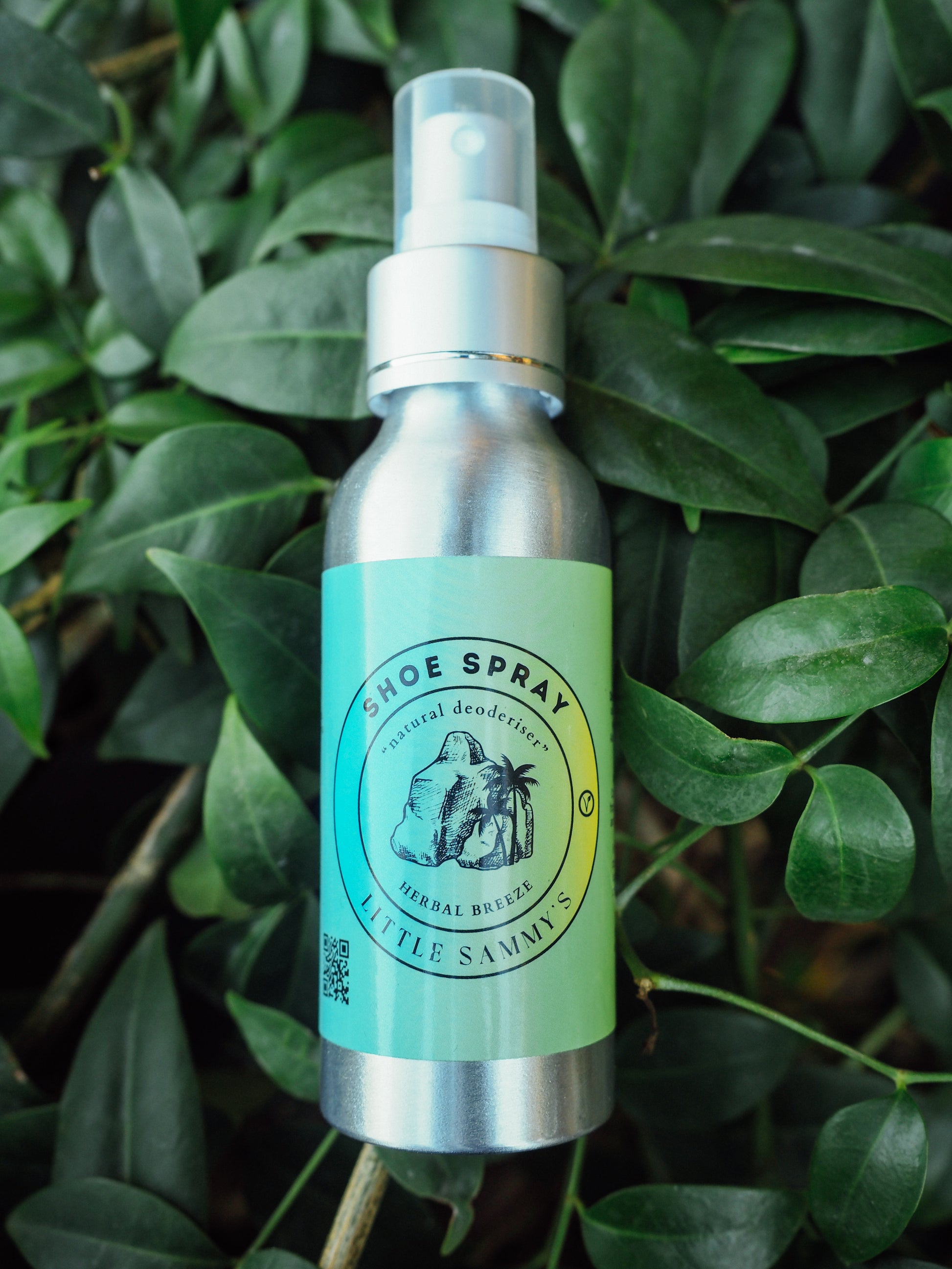 Little Sammy's Herbal Breeze Shoe Spray - A natural deodoriser spray bottle with a green label, placed among lush green leaves, highlighting its eco-friendly and vegan nature.